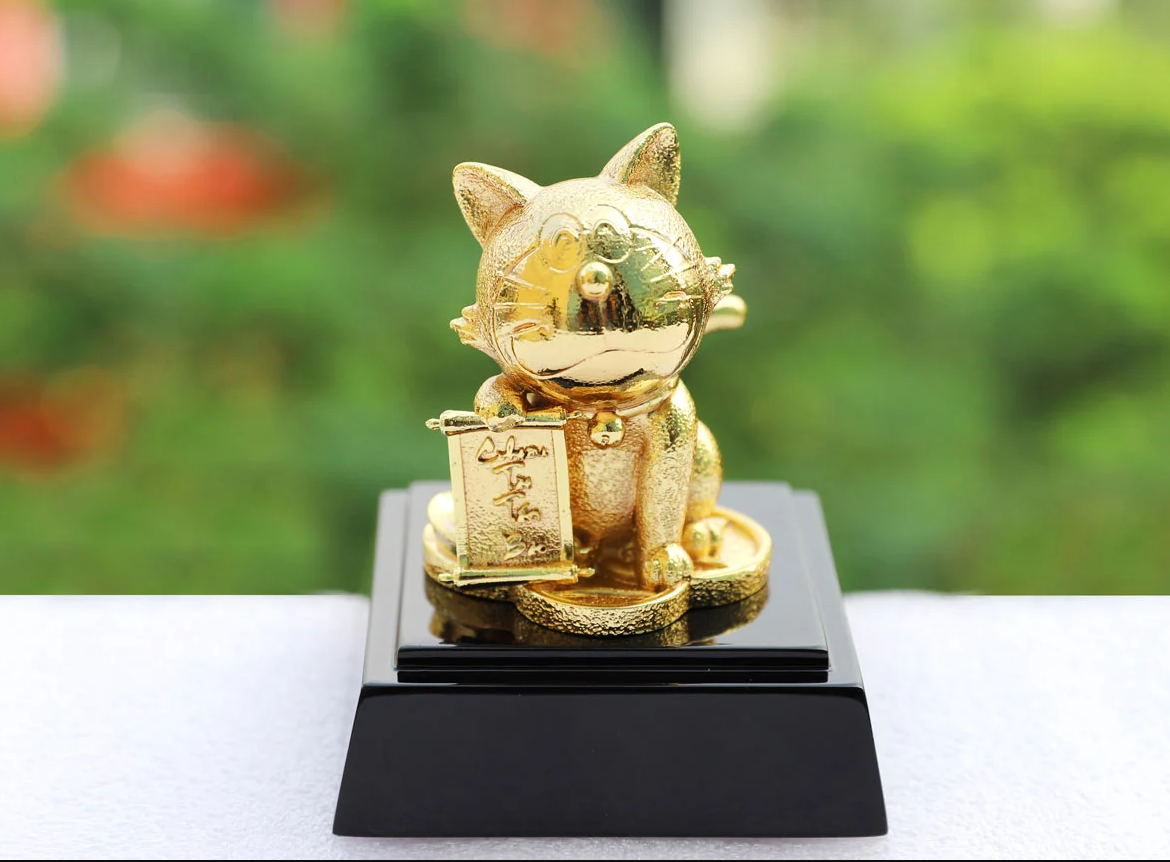Tượng mèo thần tài bên cây mai vàng.png